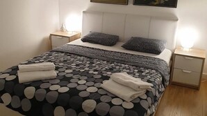 Un dormitorio con una cama, dos mesitas de noche, un espejo y dos cuadros en la pared.