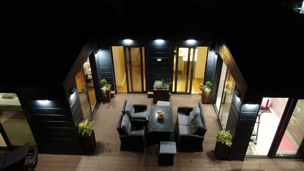 Un área de estar interior moderna con una mesa central, rodeada de sofás y plantas en macetas.