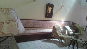Een woonkamer met een bank, een fauteuil, een bijzettafeltje en een decoratieve spiegel aan de muur.