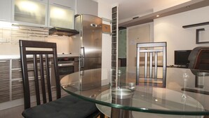 A modern kitchen with a glass dining table, stainless steel appliances, and a wooden chair. - Metropol (Belgrade)