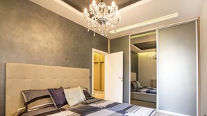 A modern bedroom with a large bed, a chandelier, and a sliding door leading to a bathroom.