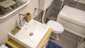 A modern bathroom with a white sink, wooden countertop, and a blue bath mat.