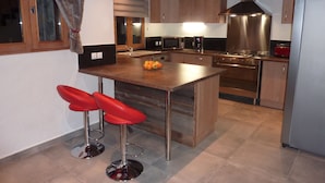 A modern kitchen with a central island, stainless steel appliances, and red bar stools. - New apartment 8 people in chalet in Champagny / La Plagne (Champagny-en-Vanoise)