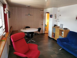 Relax in a cozy space with a round dining table, comfortable sofa, and armchair, perfect for casual dining or unwinding.