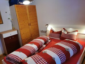 Cozy retreat with a central bed, wardrobe, and shelf.