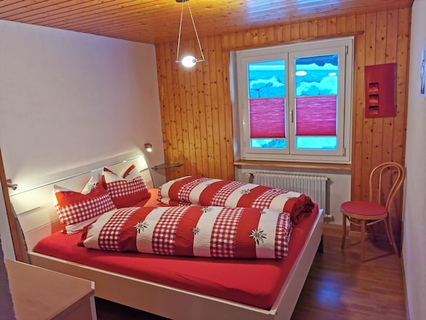 Relax in this serene bedroom with a comfortable bed, a chair by the window, and a view of the surrounding landscape.
