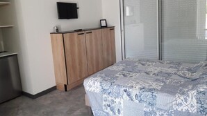 A bedroom with a bed, a television on the wall, a wardrobe, and a sliding glass door. - La Maison Familiale (Lagarrigue)