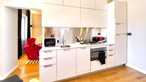 Una cocina moderna con armarios blancos, microondas, estufa y cafetera.
