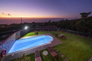 A backyard with a swimming pool, a wooden deck, and a view of the ocean at sunset. - Felicidade Rocha II - For families, with a pool (Ponta do Pargo)