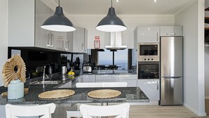 A modern kitchen with two pendant lights, a stainless steel refrigerator, and a view of the ocean. - Felicidade Rocha II - For families, with a pool (Ponta do Pargo)