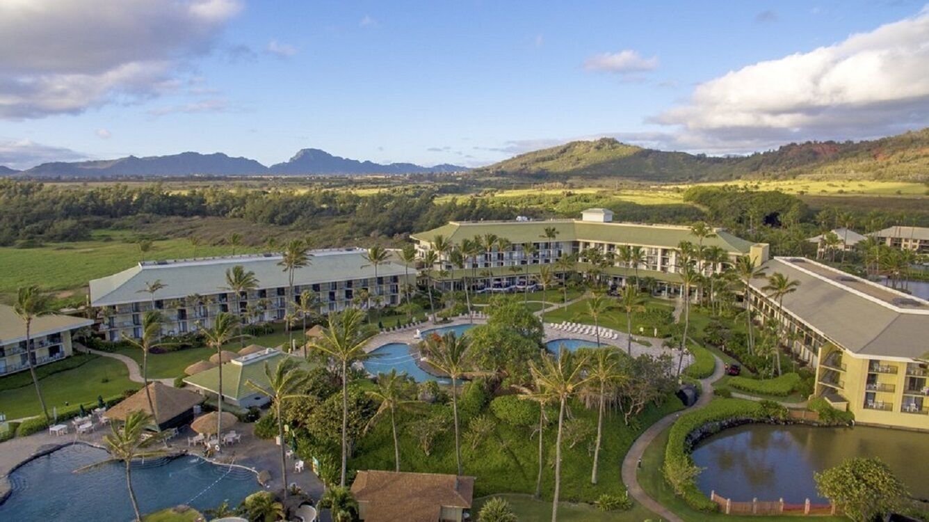 A resort with multiple buildings, a swimming pool, and a landscaped area with palm trees.