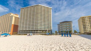 A beachfront hotel with multiple high-rise buildings, a sandy beach, and beach chairs. - Gulf Shores condo with fabulous views of the Gulf of America (Gulf Shores)