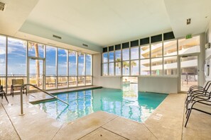 An indoor swimming pool with clear views of palm trees and a building outside. - Gulf Shores condo with fabulous views of the Gulf of America (Gulf Shores)