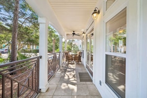 A covered outdoor area with a ceiling fan, a table with chairs, and a railing.