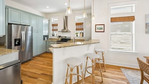 Una cocina moderna con electrodomésticos de acero inoxidable, una isla central con taburetes y una zona de comedor con vistas.