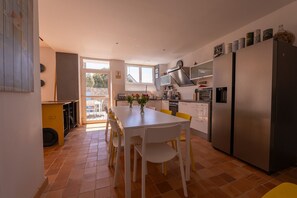 A modern kitchen with a dining table, chairs, a refrigerator, and a window. - Ti Nalu, a large family home near the beaches (Plouharnel)