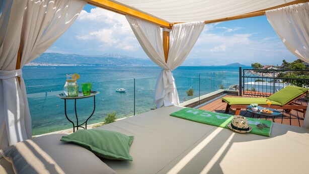 A balcony with a bed, a table with drinks, and a view of the sea and mountains. - Villa Arbanessa with Heated Pool (Arbanija)