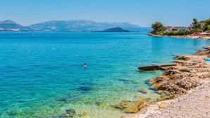 A coastal scene with clear turquoise water, rocky shoreline, and distant mountains. - Villa Arbanessa with Heated Pool (Arbanija)