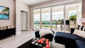 Una sala de estar moderna con vistas a una piscina y una playa, una puerta corredera de vidrio y una zona de estar acogedora.