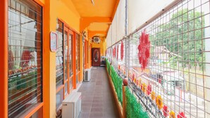 Ein Korridor mit orangefarbenen Wänden, einem gefliesten Boden und einem Metallzaun mit bunten Verzierungen.