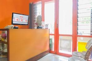 A reception area with a Samsung monitor displaying the OYO logo, a telephone, and a glass partition. - Hotel O Superbedroom (Depok)