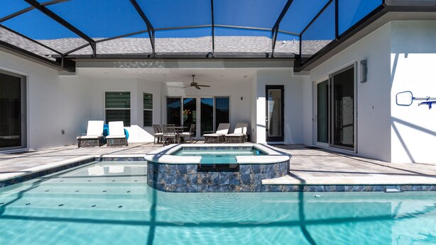 A swimming pool with a glass ceiling, lounge chairs, and a ceiling fan. - Paradise at Providence by VillaDirect (Davenport)