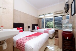 Habitación de hotel con dos camas, un lavamanos, dispensador de agua y ventana con vistas.