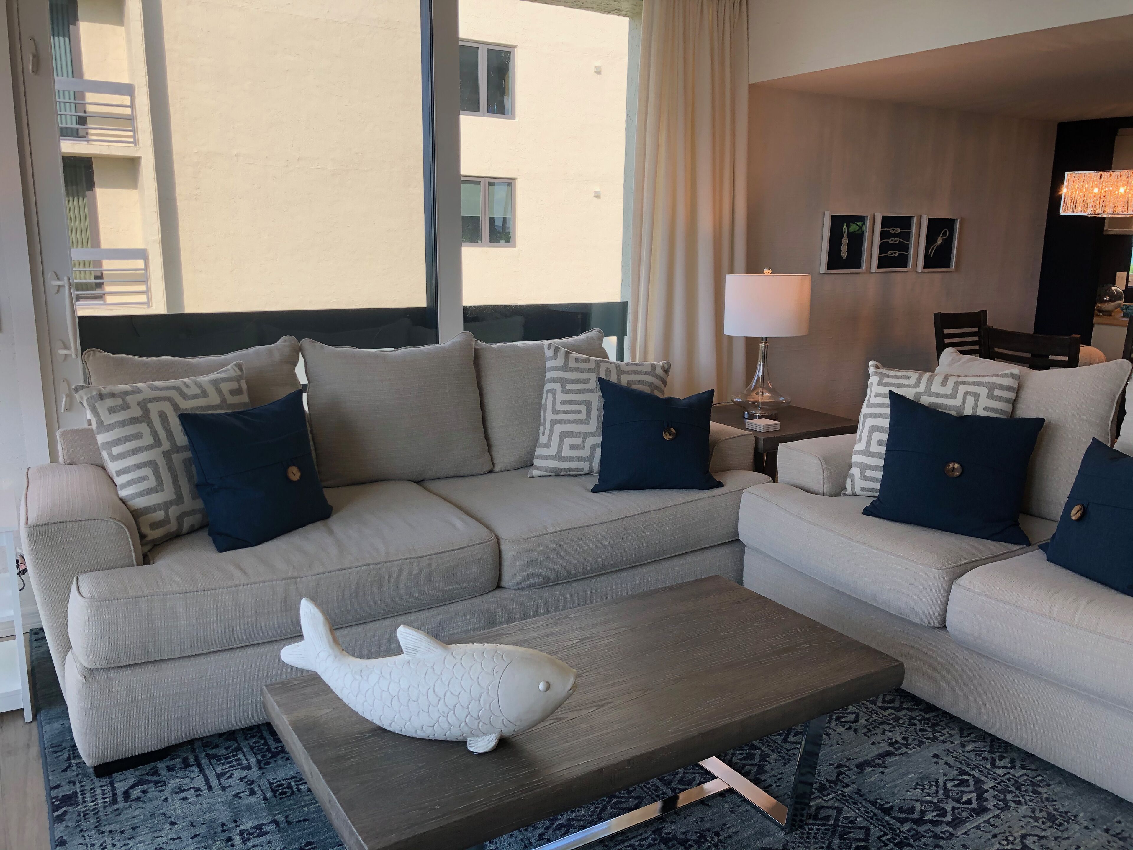 A modern living room with a beige sectional sofa, a wooden coffee table, and a decorative fish sculpture.