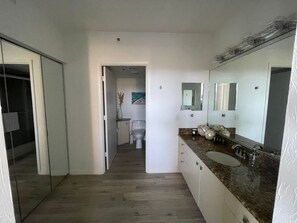 A modern bathroom with a large mirror, a sink, and a toilet. - Ocean View Condo with Beach Access at Beachplace (Longboat Key)