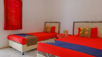 Una habitación con dos camas, cada una con ropa de cama roja y almohadas estampadas.