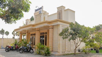 Un edificio con fachada de tejas, un acceso cubierto y dos motocicletas estacionadas frente a él.