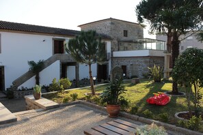 A courtyard with a stone building, a wooden bench, and a red children's play structure.