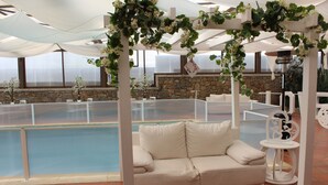 An indoor pool area with a white sofa and a small table, surrounded by stone walls and white columns. - Solar Do Areal (Braga)
