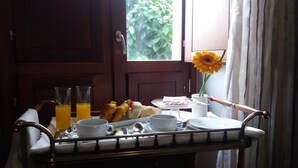 A breakfast tray with croissants, juice glasses, and a vase with a single flower. - Solar Do Areal (Braga)