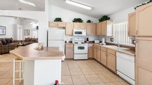 Una cocina moderna con una isla central, electrodomésticos blancos y armarios de madera.