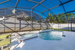 A swimming pool with a hot tub, surrounded by a covered area with lounge chairs. - Neptunes Retreat Villa by VillaDirect (Kissimmee)