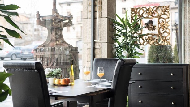 Een restauranttafel met een fles wijn, een glas sinaasappelsap en een schaal fruit.
