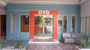 Entrada de un edificio con un letrero que dice "OYO" y un área de recepción con un sofá y una planta.