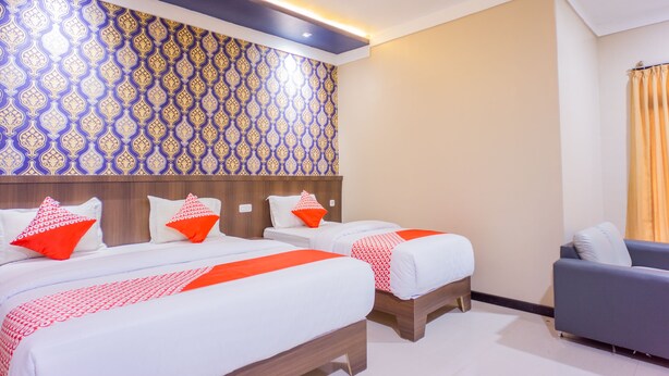 Habitación de hotel con dos camas, un sofá y un papel tapiz estampado.