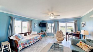 A spacious living room with a large bed, a sofa, a chair, and a glass coffee table. - Walk to Sandfest, Shared Pools, Boardwalk to the Beach (Port Aransas)