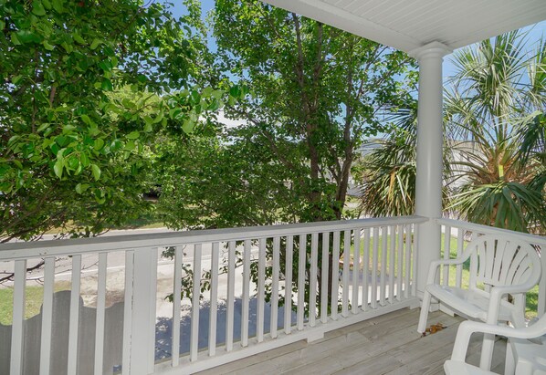 A covered porch with white railings and a white chair. - 5-Bedroom Home w/ Pool & Private Beach Access (Surfside Beach)