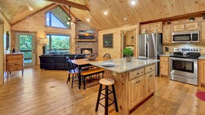 A spacious kitchen with wooden cabinetry, a central island, and modern appliances. - Amazing mountain view cabin, Hot tub, wifi near Mercier Orchards! (Blue Ridge)