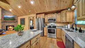 A modern kitchen with wooden cabinets, granite countertops, stainless steel appliances, and a fireplace. - Amazing mountain view cabin, Hot tub, wifi near Mercier Orchards! (Blue Ridge)