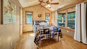A bedroom with a wooden ceiling, a bed with a checkered blanket, two windows, and a ceiling fan. - Amazing mountain view cabin, Hot tub, wifi near Mercier Orchards! (Blue Ridge)