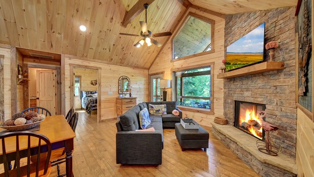 A spacious living area with a fireplace, wooden ceiling, and large windows. - Amazing mountain view cabin, Hot tub, wifi near Mercier Orchards! (Blue Ridge)