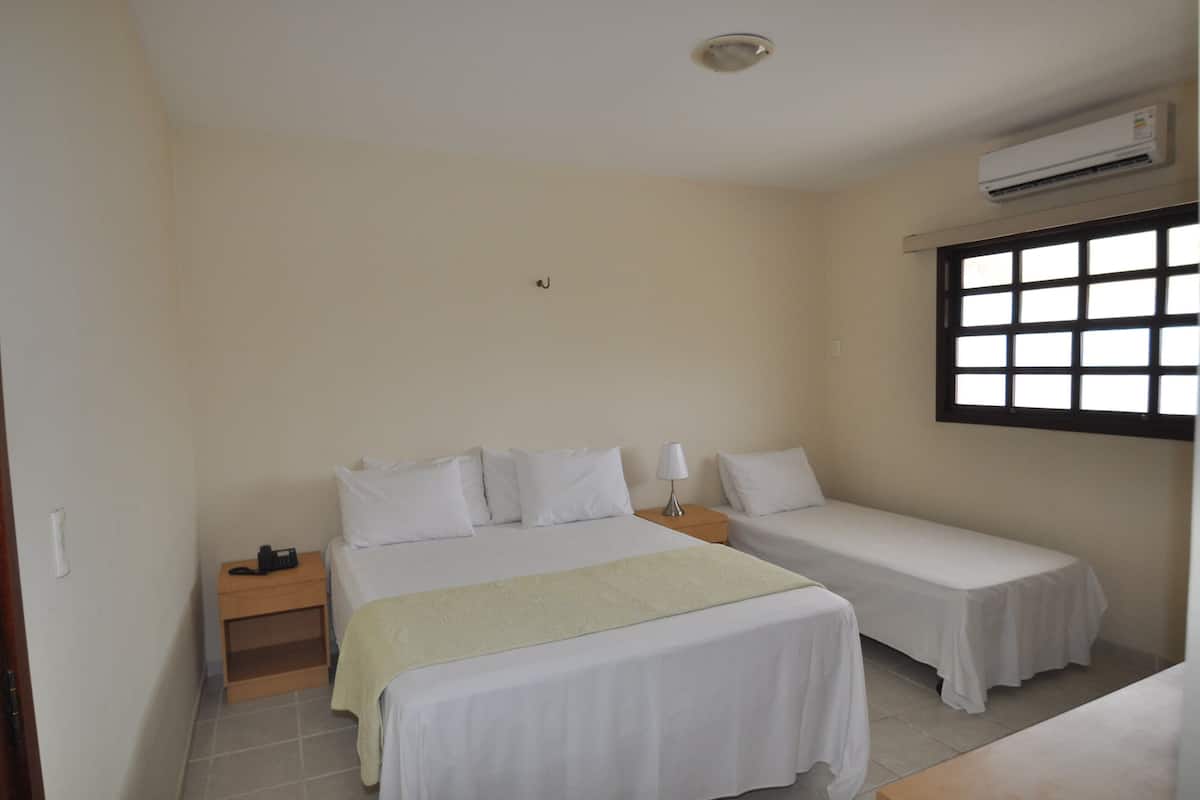 A bedroom with two single beds, a nightstand, a bedside table, and a window with blinds.