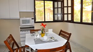 Un comedor con una mesa dispuesta para dos personas, microondas y ventana con vistas al exterior.