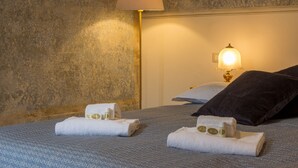 Quarto de hotel com cama, abajur e toalhas.
