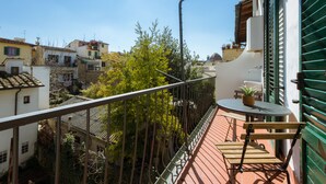 Varanda com mesa e cadeira, vista para uma área residencial com casas e árvores.