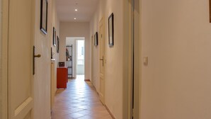Um corredor com quadros nas paredes, um armário vermelho e uma porta no final.